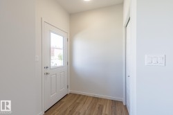 Entryway featuring a paneled door with an integrated window, wood-finish flooring, a built-in closet with bifold doors, and a flush-mount ceiling light - 