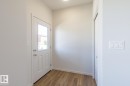 Entryway featuring a paneled door with an integrated window, wood-finish flooring, a built-in closet with bifold doors, and a flush-mount ceiling light - 3619 Triomphe Boulevard, Beaumont, AB  - Indoor Photo Showing Other Room 