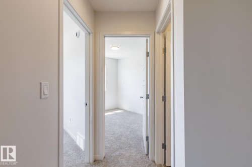 Interior hallway featuring light grey wall paint, white trim, and light grey carpet - 3619 Triomphe Boulevard, Beaumont, AB - Indoor Photo Showing Other Room