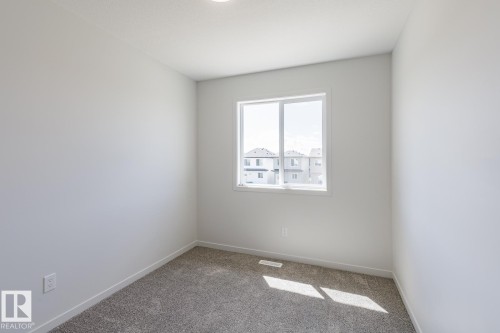 Carpeted room featuring a white-framed window, neutral painted walls, and recessed ceiling lighting - 3619 Triomphe Boulevard, Beaumont, AB - Indoor Photo Showing Other Room