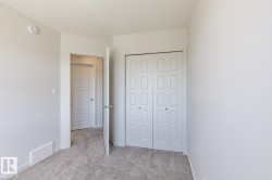 Neutral-toned room featuring a bifold closet, light gray carpeting, white trim, and a white interior door with a silver-tone knob - 