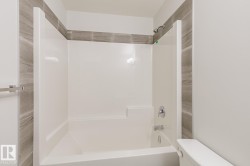White bathtub and shower combination unit featuring a chrome shower head and faucet - 