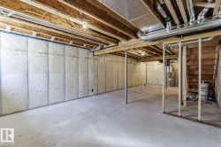 Unfinished basement featuring exposed wood joists, concrete flooring, insulated perimeter walls, and visible ductwork - 