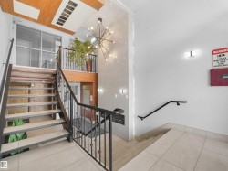 Multi-level interior featuring a contemporary chandelier, wrought iron railings, and wood-finish ceiling accents - 