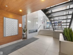 Lobby featuring wood-finish wall paneling, integrated mailbox system, a linear electric fireplace, and a contemporary metal staircase - 