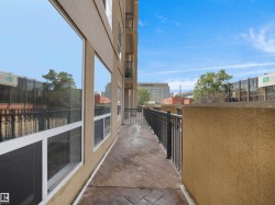 Exterior balcony featuring stamped concrete flooring, black metal railing, and a stucco wall - 