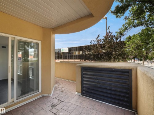 Private outdoor patio with stamped concrete flooring and a textured stucco privacy wall - #207 10606 102 Av Nw, Edmonton, AB 