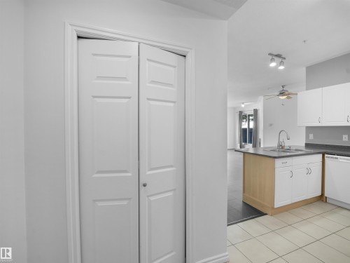 Kitchen with an island featuring a sink, stainless steel faucet, and white cabinetry - #207 10606 102 Av Nw, Edmonton, AB 
