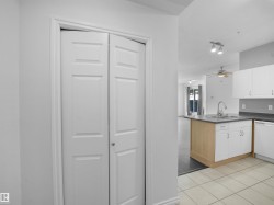 Kitchen with an island featuring a sink, stainless steel faucet, and white cabinetry - 