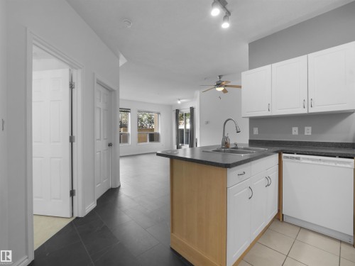 Kitchen featuring white cabinetry, gray countertops, and an integrated dishwasher - #207 10606 102 Av Nw, Edmonton, AB 