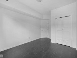 Spacious room featuring dark tile flooring with subtle veining, white baseboards, and bright white walls - 