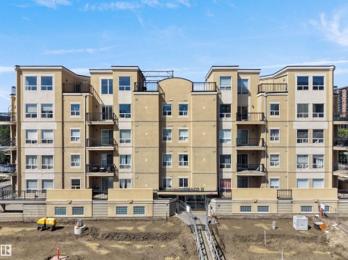 Multi-story residential building featuring a light-colored stucco exterior with contrasting cream-colored banding - #207 10606 102 Av Nw, Edmonton, AB 