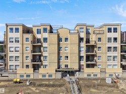 Multi-story residential building featuring a light-colored stucco exterior with contrasting cream-colored banding - 