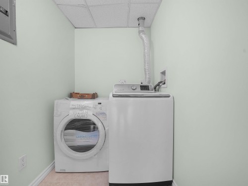 Dedicated laundry area featuring light-toned walls, white trim, and a drop ceiling - #207 10606 102 Av Nw, Edmonton, AB 