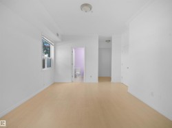 Spacious room featuring light wood-finish flooring, white baseboards, and bright white walls - 