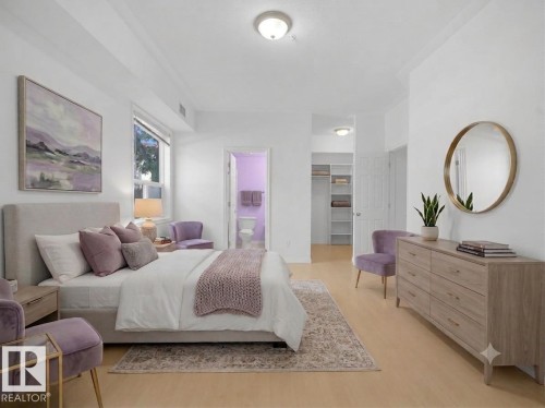 Spacious bedroom featuring light wood-finish flooring, a contemporary ceiling light fixture, a window with exterior views, an open doorway leading to a walk-in closet with shelving, and an additional doorway opening into a bathroom - #207 10606 102 Av Nw, Edmonton, AB 