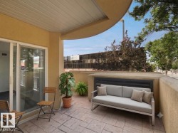 Private patio space featuring stamped concrete flooring and a curved exterior wall - 