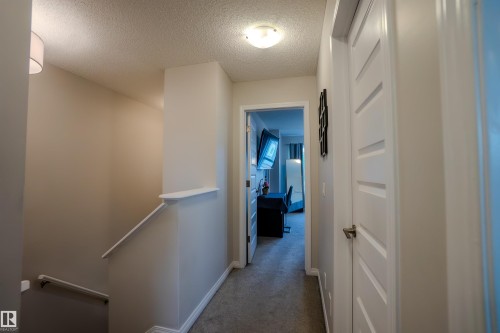 Hallway featuring neutral-toned walls, textured ceiling, flush mount lighting, and carpet flooring - 1766 Dumont Crescent Sw, Edmonton, AB 