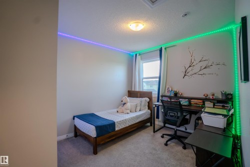 Carpeted room featuring a single window with curtain rods and drapes, a flush-mount ceiling light fixture, and perimeter wall-mounted lighting strips - 1766 Dumont Crescent Sw, Edmonton, AB 