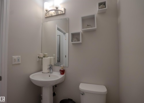 Pedestal sink with chrome faucet, large rectangular mirror, and wall-mounted light fixture - 1766 Dumont Crescent Sw, Edmonton, AB 