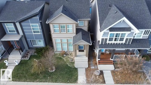 Beige two-story home featuring a covered front entry, multiple windows with white trim, and a concrete pathway leading to the front door - 1766 Dumont Crescent Sw, Edmonton, AB 