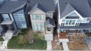 Beige two-story home featuring a covered front entry, multiple windows with white trim, and a concrete pathway leading to the front door - 1766 Dumont Crescent Sw, Edmonton, AB 