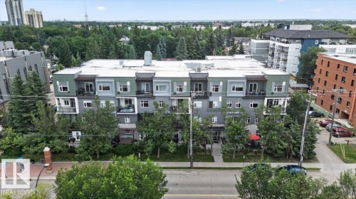 Modern multi-story building featuring balconies with glass railings, a grey and green facade, and a flat roofline - #406 8525 91 St Nw, Edmonton, AB 