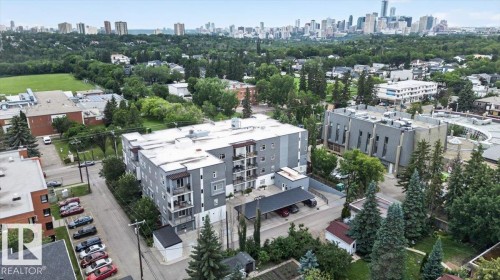 Modern multi-story building featuring gray exterior siding, multiple private balconies, and covered parking - #406 8525 91 St Nw, Edmonton, AB 