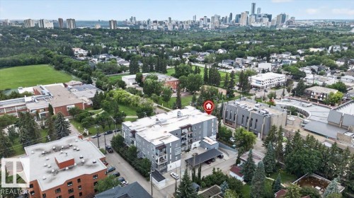 Modern multi-story building featuring balconies and carports, surrounded by mature trees and urban landscaping - #406 8525 91 St Nw, Edmonton, AB 