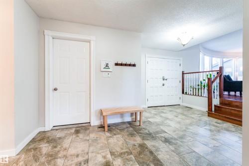 Entryway featuring tile flooring, white double doors, a white interior door with a round knob, dark wood stairs, and a white baluster railing - 5212 142 Street Nw, Edmonton, AB - Indoor Photo Showing Other Room