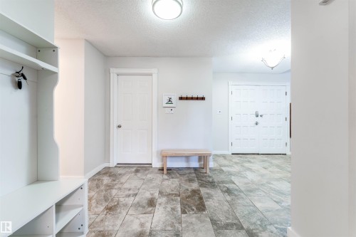 Entryway featuring large format tile flooring, a built-in storage unit with shelving, a contemporary flush mount ceiling light, and a double entry door with decorative panels - 5212 142 Street Nw, Edmonton, AB - Indoor Photo Showing Other Room