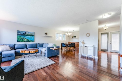 Spacious living area featuring rich wood-finish flooring, recessed lighting, and a bright dining area with a contemporary chandelier - 5212 142 Street Nw, Edmonton, AB - Indoor Photo Showing Living Room