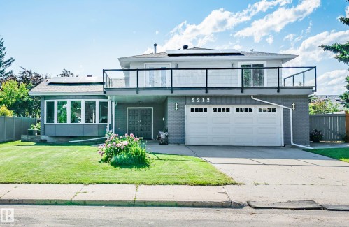 Contemporary exterior featuring a two-car garage, upper-level balcony with glass railings, a bay window, and rooftop solar panels - 5212 142 Street Nw, Edmonton, AB - Outdoor