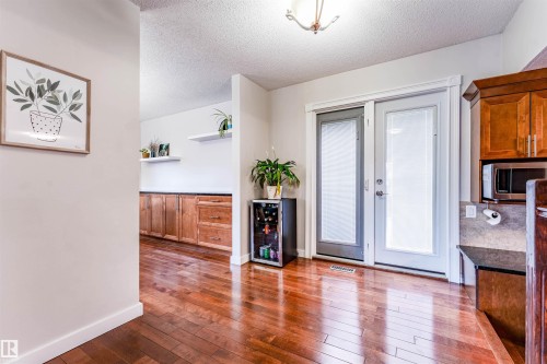 Rich wood-finish flooring complements the warm-toned cabinetry - 5212 142 Street Nw, Edmonton, AB - Indoor Photo Showing Other Room