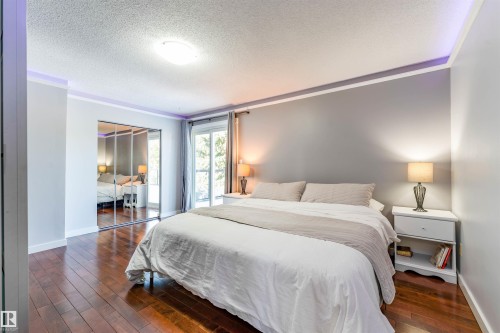 Bedroom featuring wood-finish flooring, mirrored closet doors, and recessed ceiling lighting - 5212 142 Street Nw, Edmonton, AB - Indoor Photo Showing Bedroom