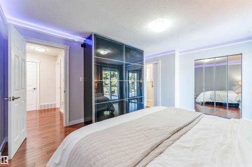 Bedroom featuring wood-finish flooring, two sets of mirrored closet doors, and recessed ceiling lighting - 5212 142 Street Nw, Edmonton, AB - Indoor Photo Showing Bedroom