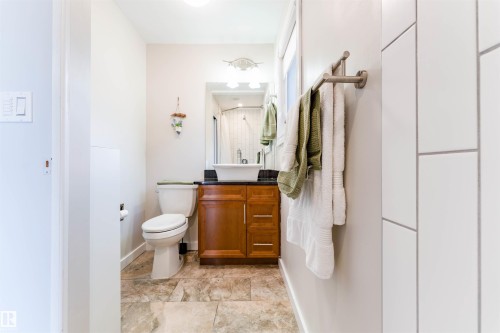 Bathroom featuring a wood-finish vanity with a dark countertop, vessel sink, and stone-look tile flooring - 5212 142 Street Nw, Edmonton, AB - Indoor Photo Showing Bathroom