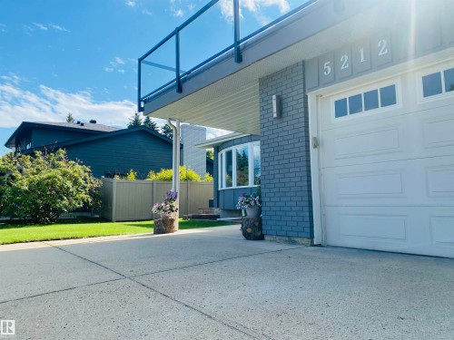 Concrete driveway leading to a white panel garage door with upper window inserts - 5212 142 Street Nw, Edmonton, AB - Outdoor