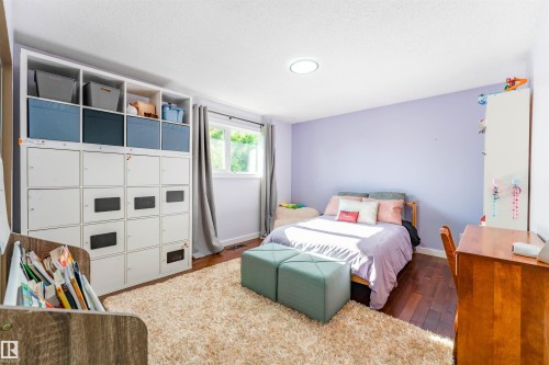 Bedroom featuring dark wood-finish flooring and a single window with drapes - 5212 142 Street Nw, Edmonton, AB - Indoor Photo Showing Bedroom