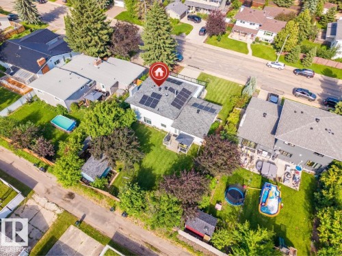 Aerial view showcasing a residential property with a gray shingle roof, solar panel array, and expansive green lawn - 5212 142 Street Nw, Edmonton, AB - Outdoor With View
