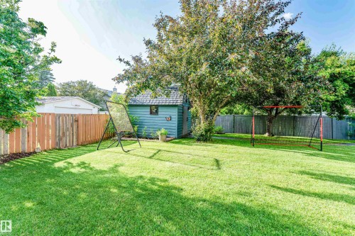 Spacious rear yard with a manicured lawn, established shade trees, and a wooden privacy fence - 5212 142 Street Nw, Edmonton, AB - Outdoor