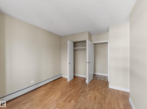 Room featuring wood-finish flooring, neutral wall paint, and white baseboards - #502 9710 105 St Nw, Edmonton, AB 