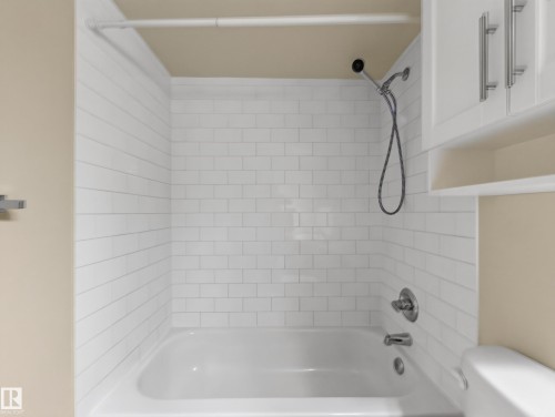 Bathtub with white subway tile surround, chrome fixtures, and a handheld showerhead - #502 9710 105 St Nw, Edmonton, AB 
