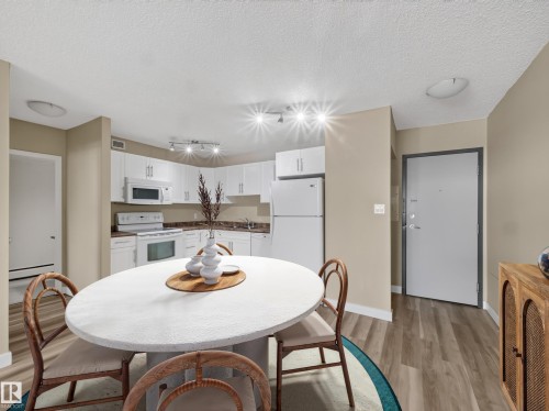 Open-concept kitchen featuring white cabinetry, white appliances, and track lighting - #502 9710 105 St Nw, Edmonton, AB 