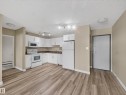Open-concept kitchen featuring white cabinetry, a complete suite of white appliances, track lighting, and wood-finish flooring - #502 9710 105 St Nw, Edmonton, AB 