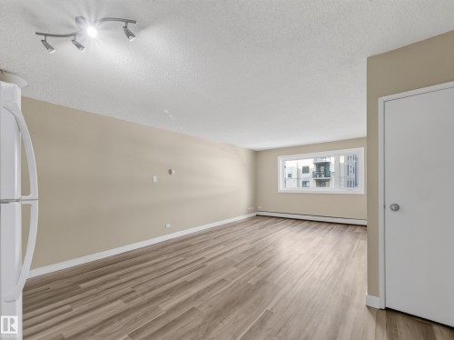 Open living area featuring wood-finish flooring and neutral wall tones - #502 9710 105 St Nw, Edmonton, AB 