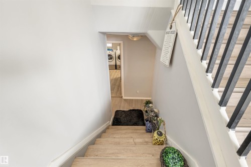 Staircase featuring wood-finish treads, white risers, and a contemporary black metal baluster system - 2437 89 Street Nw, Edmonton, AB 