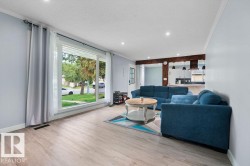 Bright living area featuring wood-finish flooring, recessed ceiling lighting, and a large picture window - 