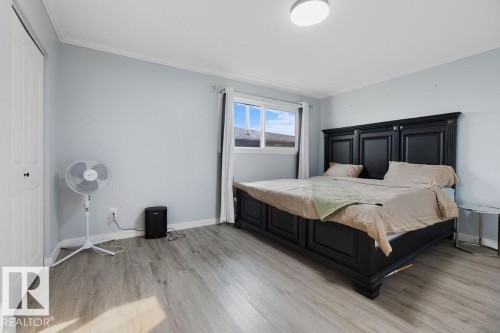 Spacious bedroom featuring wood-finish flooring, a double-paned window, and a built-in closet with bifold doors - 27 Apache Crescent, Leduc, AB 