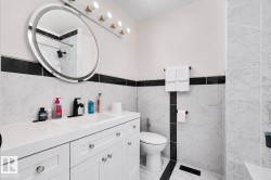 Bathroom featuring a white vanity with integrated sink, matte black faucet, and round illuminated mirror - 